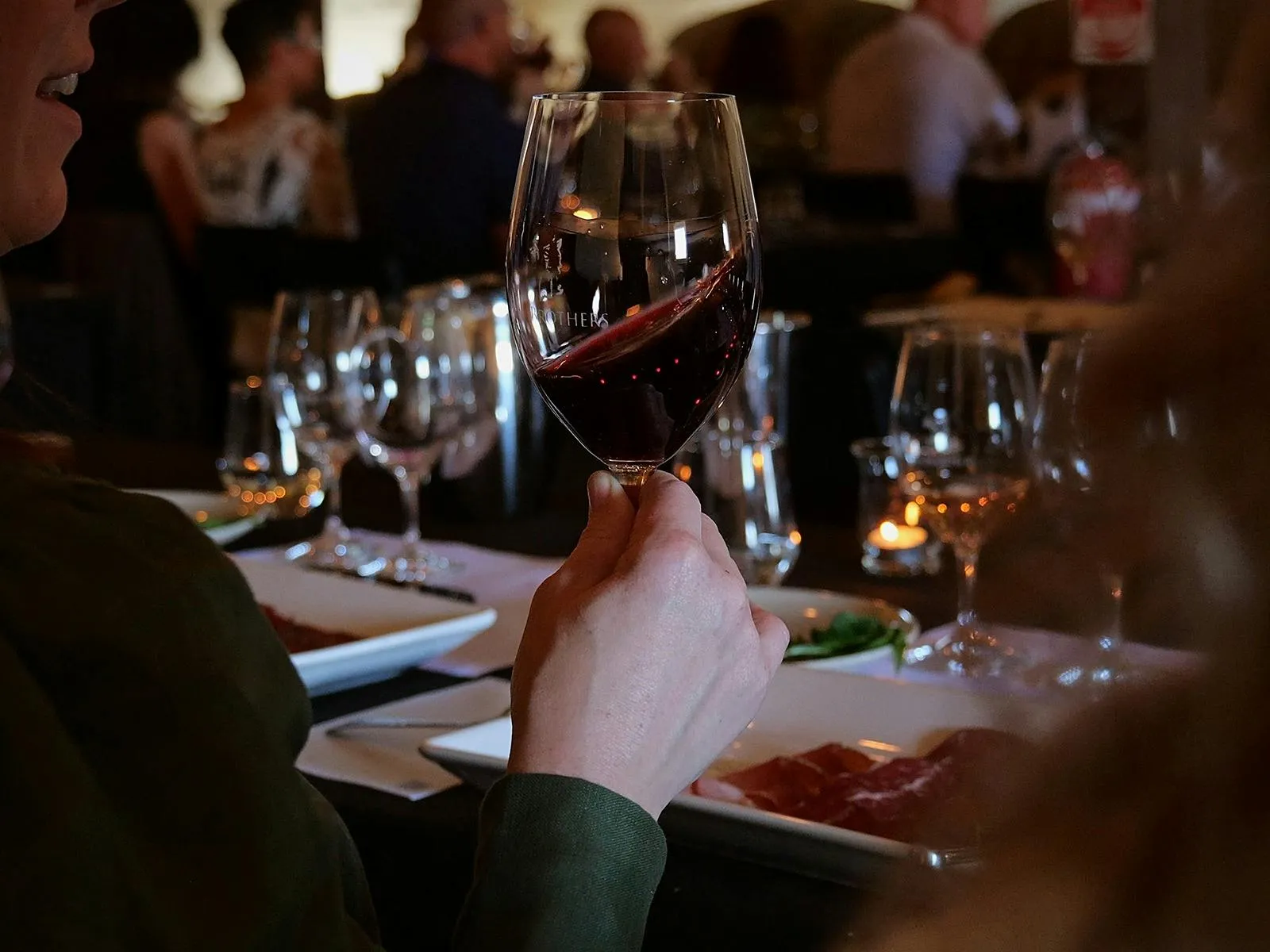 Guests enjoying glasses of red wine at a winery tasting or long lunch in McLaren Vale.